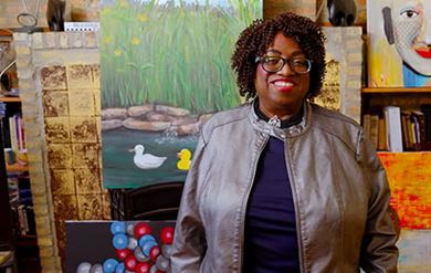 Stroke survivor, Minnie, is standing in a studio surrounded by her paintings. Stroke survivor, Minnie, is standing in a studio surrounded by her paintings.