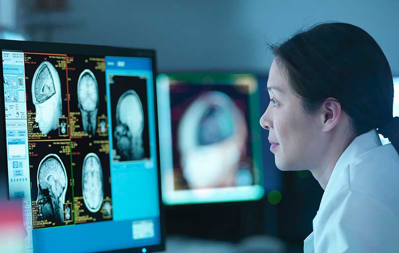 female medical researcher looking at brain scans on monitor