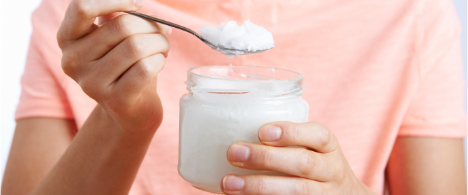 photo of woman holding spoonful of coconut oil
