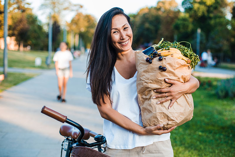 middle-aged woman carrying grocery bad on bike
