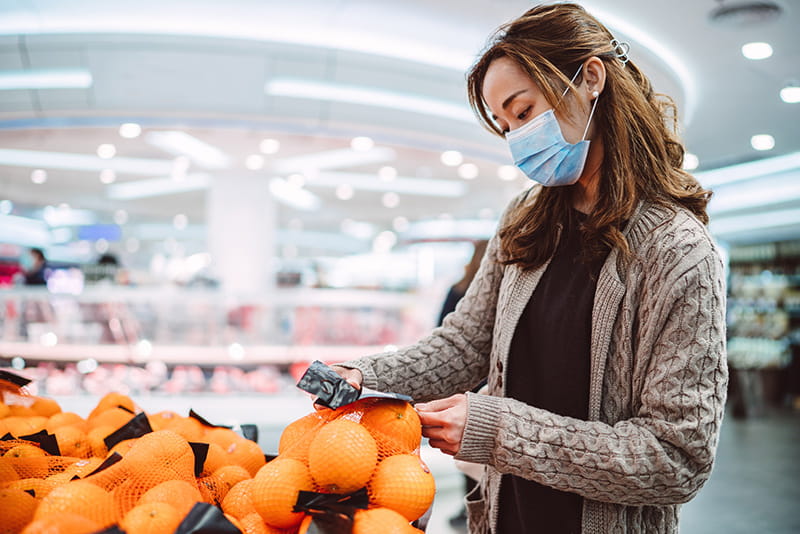 Woman grocery shopping in mask