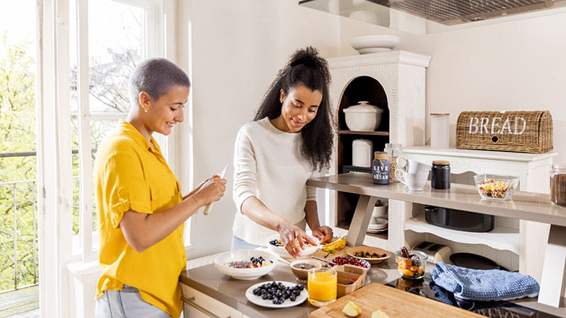 Two young women making a healthy breakfast in the kitchen.