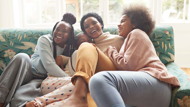 Portrait of happy woman embracing girls at home
