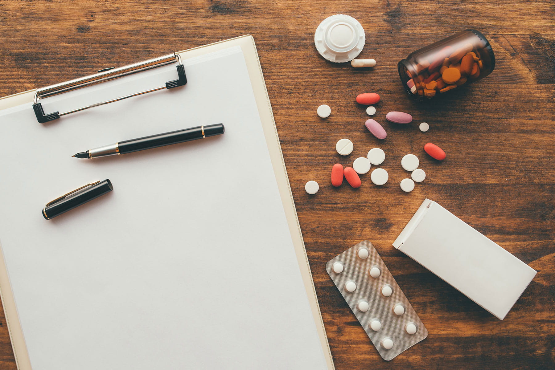 overhead view of medical doctor office desk with medication and notepad