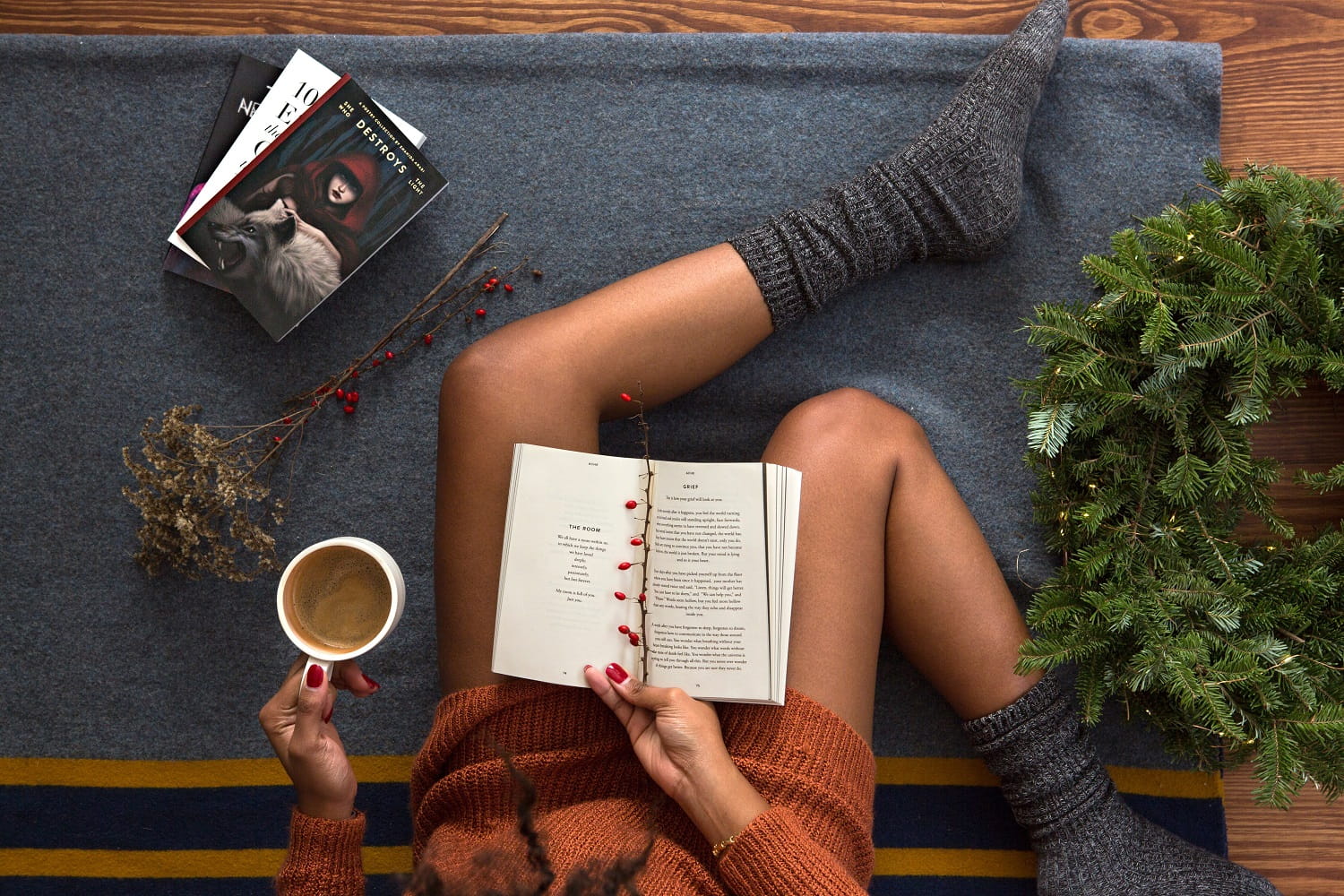 Overhead shot of women in socks reading book with coffee and festive decor