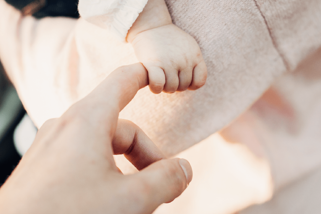 image of a baby's hand holding an adult's hand