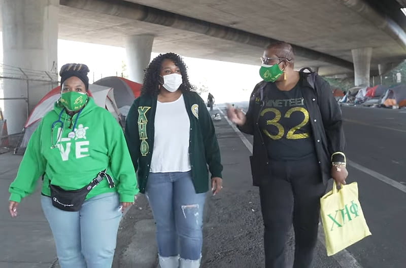 three volunteers walking through urban homeless camp