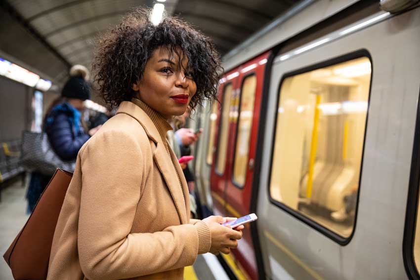 woman waiting for train holding phone