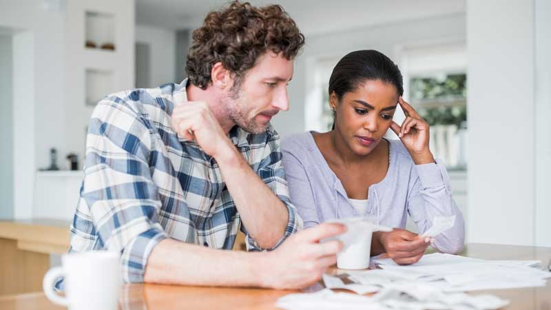 Couple sitting at kitchen table looking at their bills