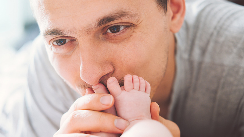 father kisses baby foot
