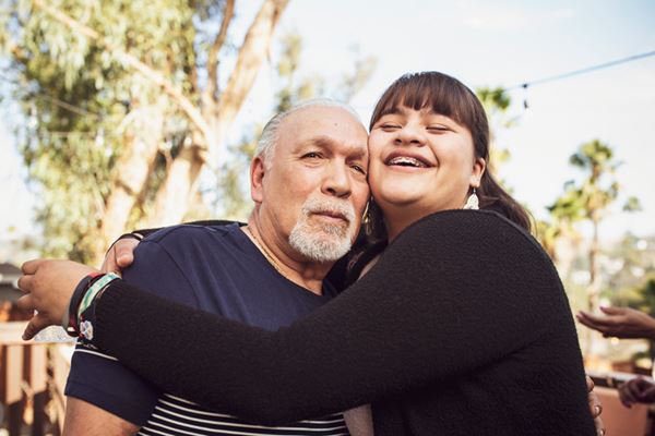 Older man getting big hug from granddaughter