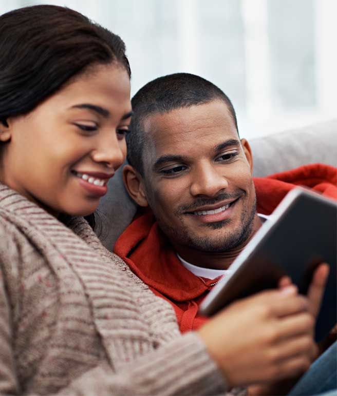 couple on couch looking at a tablet
