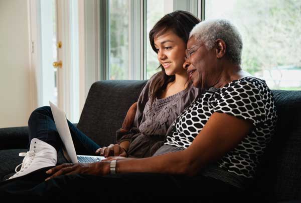 Grandmother and granddaughter researching on laptop