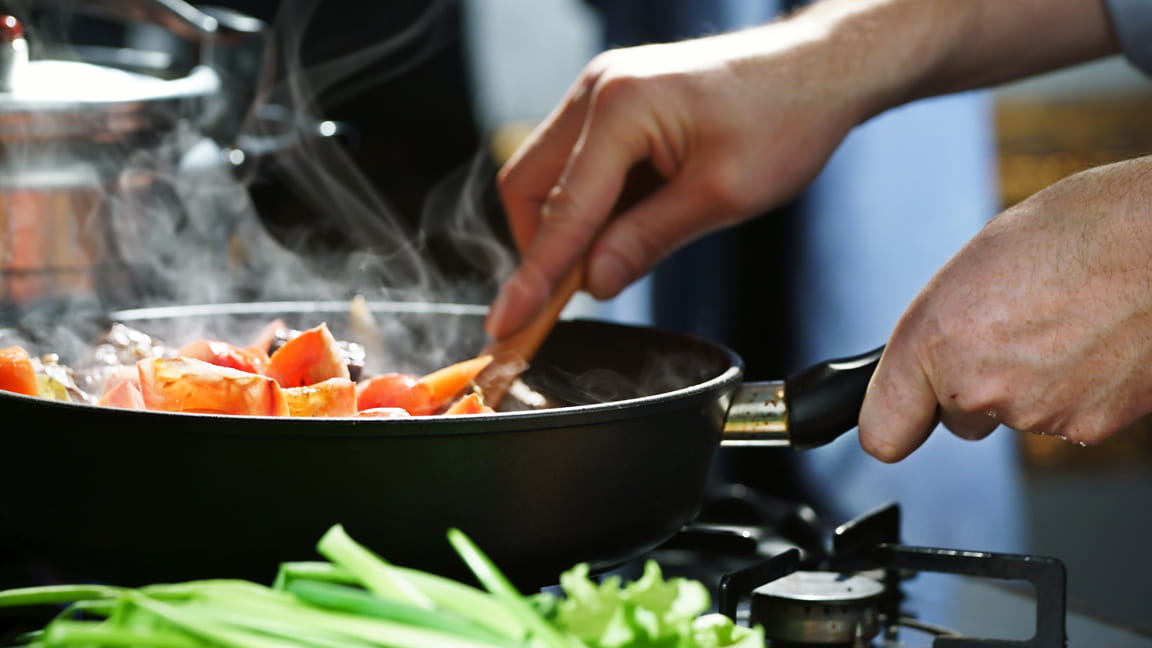 close up of hands sauteing food over store