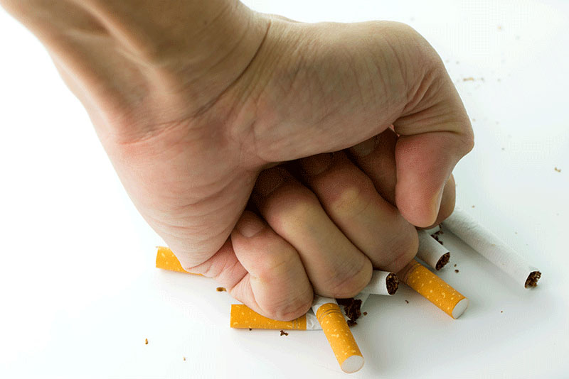 dejar de fumar; mano aplastando cigarrillos