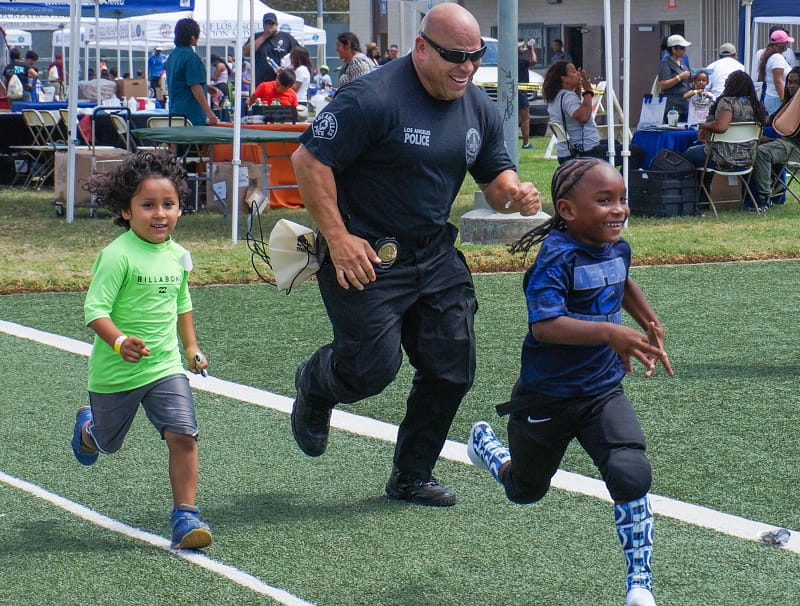 LAPD officer runs with children at Harvard Recreation Center in South Los Angeles