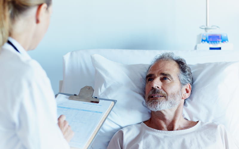 Doctor talking to man in hospital bed. (Morsa Images/Getty Images)