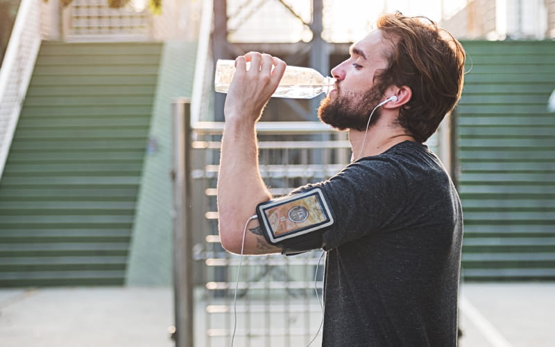 Man exercising and drinking water. (Rawpixel)