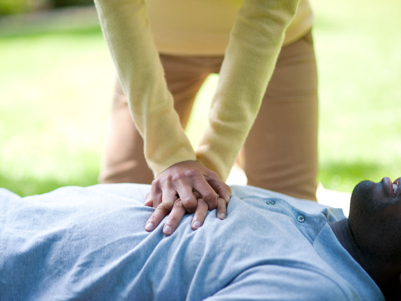 Woman doing CPR on collapsed man.