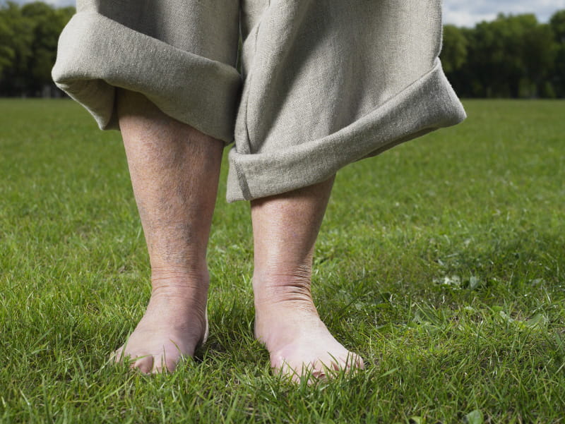 Older person walking in grass barefoot.  (Getty Images)