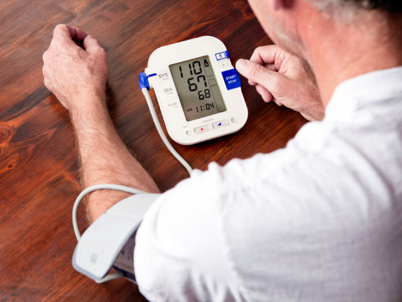 Man using blood pressure monitor. (cglade, iStockphoto)