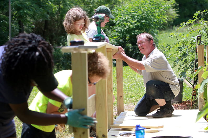 Volunteers work together to build the rail for a wheelchair ramp to make a home more accessible. (Photo courtesy of Jared Putnam)