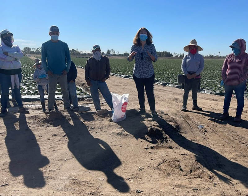 Gloria Giraldo (center) of Latino Health Access discusses COVID-19 vaccine safety and effectiveness with agricultural workers at a farm in Irvine, California. (Photo courtesy of Latino Health Access)