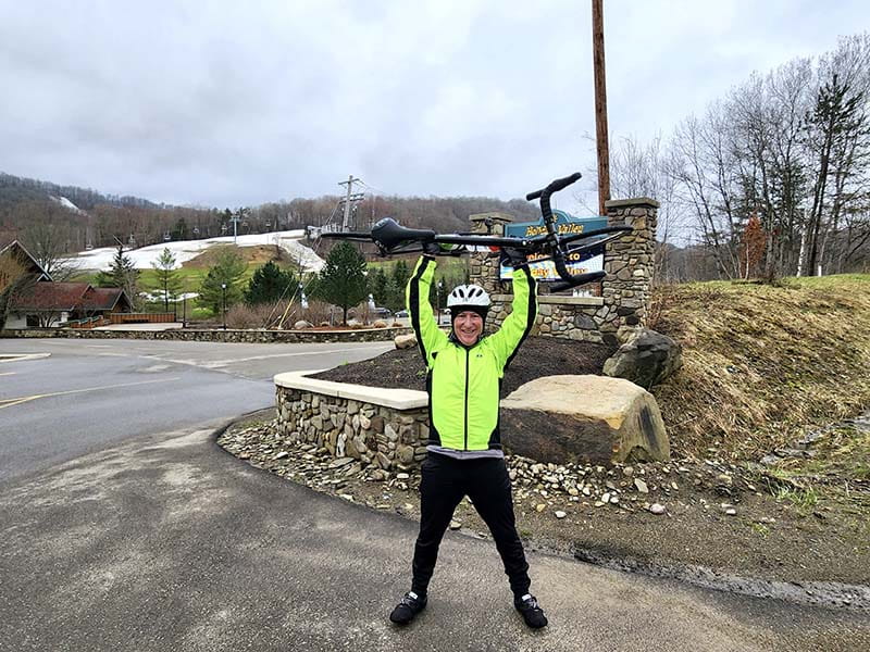 Patrick Raycraft lifts his bike overhead after completing the final 10 miles of a charity bike ride on April 5, 2025.