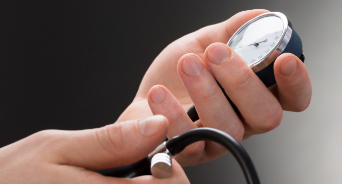 Hands holding blood pressure monitor