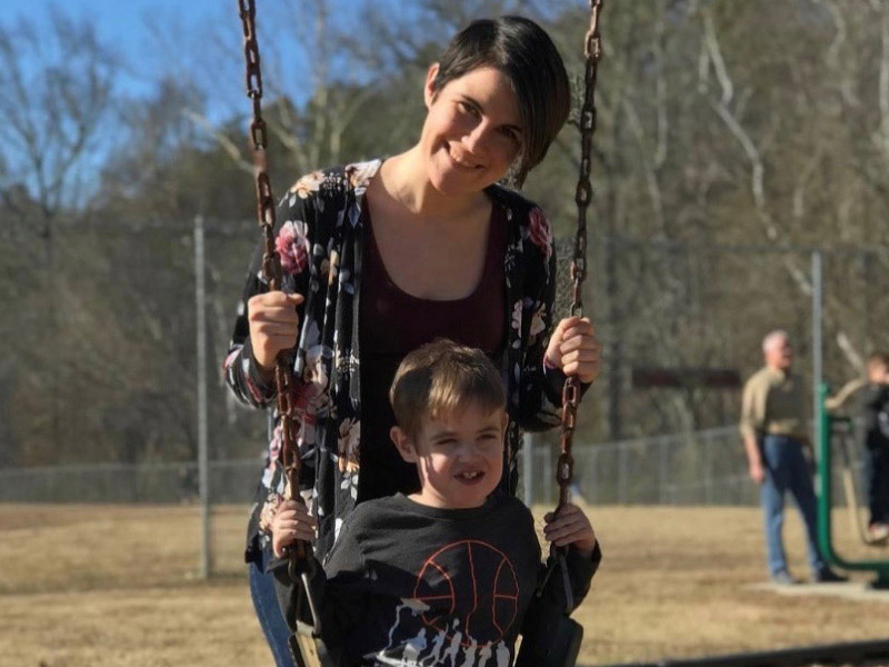 Bennett Sayles, who has survived five open-heart surgeries, smiles on a playground with his mom, Hannah Lewis. (Photo courtesy of Hannah Lewis)