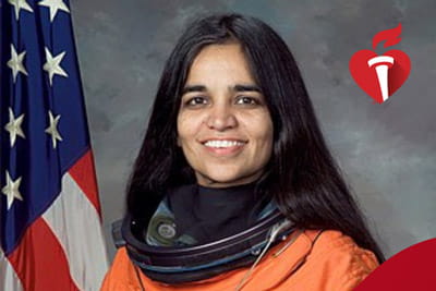 a portrait of Kalpana Chawla in her orange astronaut suit with an American flag in the background