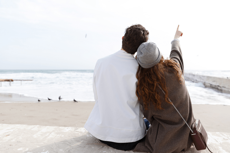 back view of couple sitting on the beach back view of couple sitting on the beach