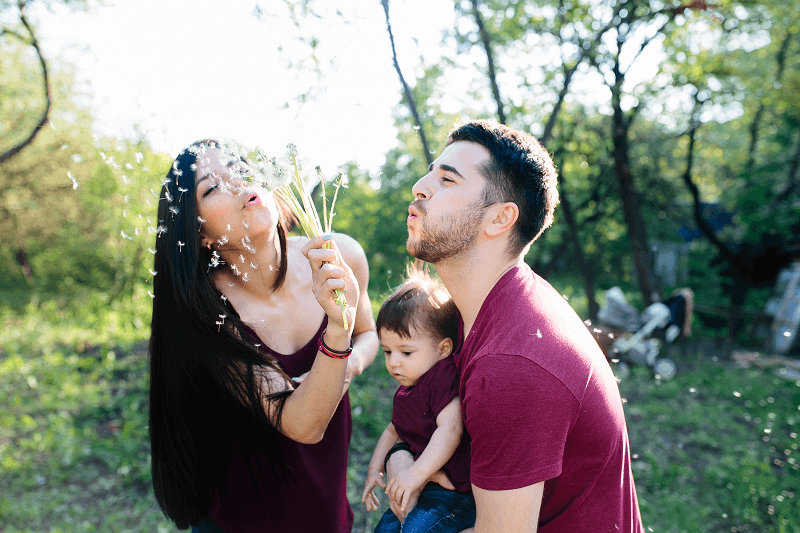 Young family and Mother is blowing flowers in the air