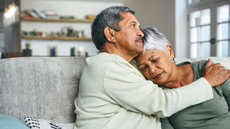 senior man holding his wife on a sofa during a difficult time at home