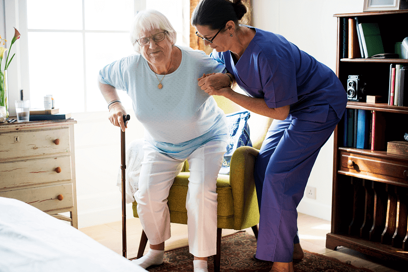 nurse helping senior woman to stand