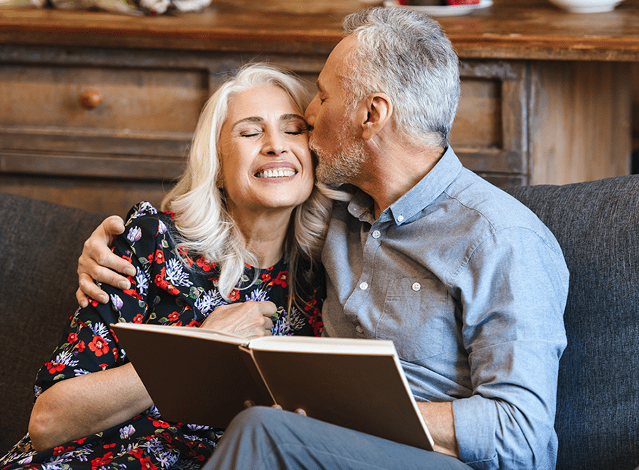 Happy mature man and woman reading a book on the couch