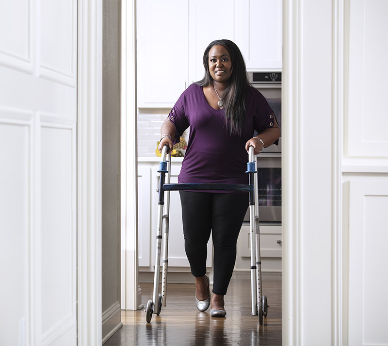 Woman walking down hallway using a walker