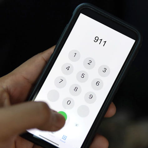 a person dialing 911 on a smartphone with their thumb