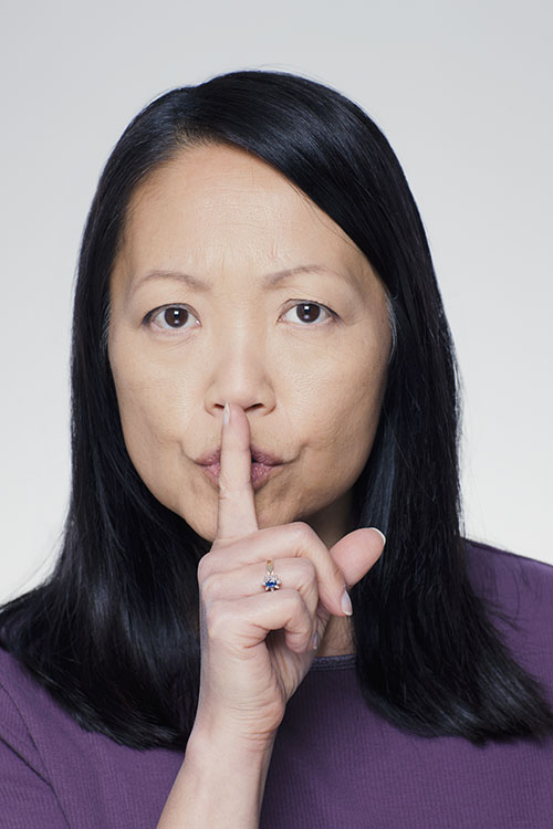 Woman with her hand to her lips to indicate silence