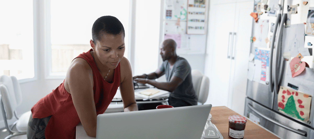 Woman standing and looking down at a laptop computer