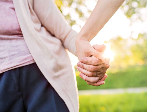 Elderly woman holding a young person's hand