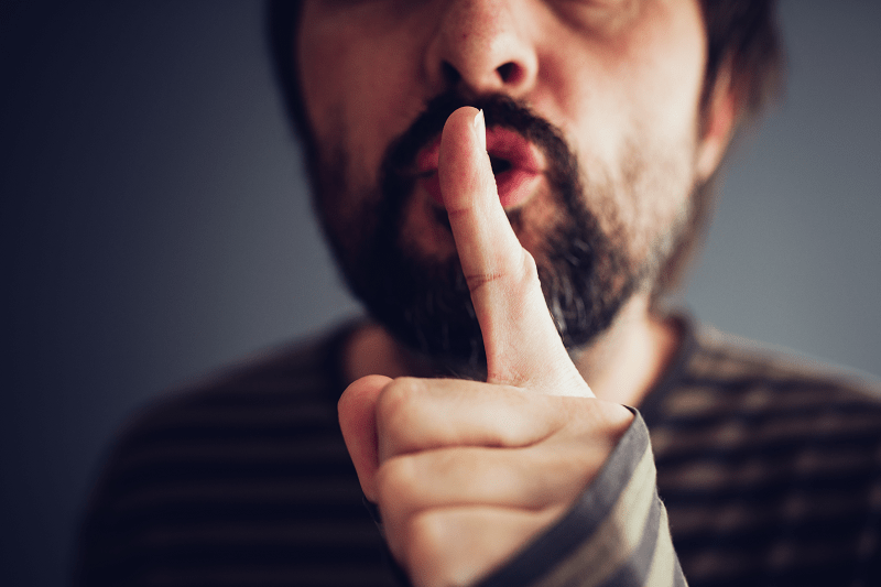 Man standing with his finger to his month, signalizing silence