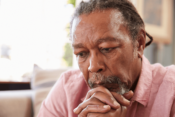 senior man sitting on sofa at home looking concerned