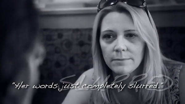 a black and white video screen shot of stroke survivor, Julie, a white woman talking with a friend indoors with the overlaying words, "Her words just completely slurred."