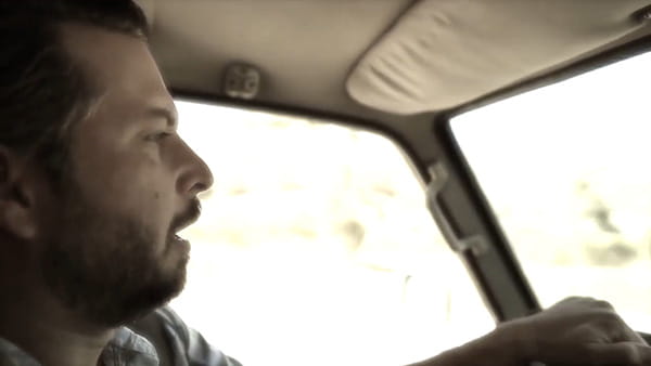 a video screen shot of stroke survivor, Stefan, a man with a beard driving a car