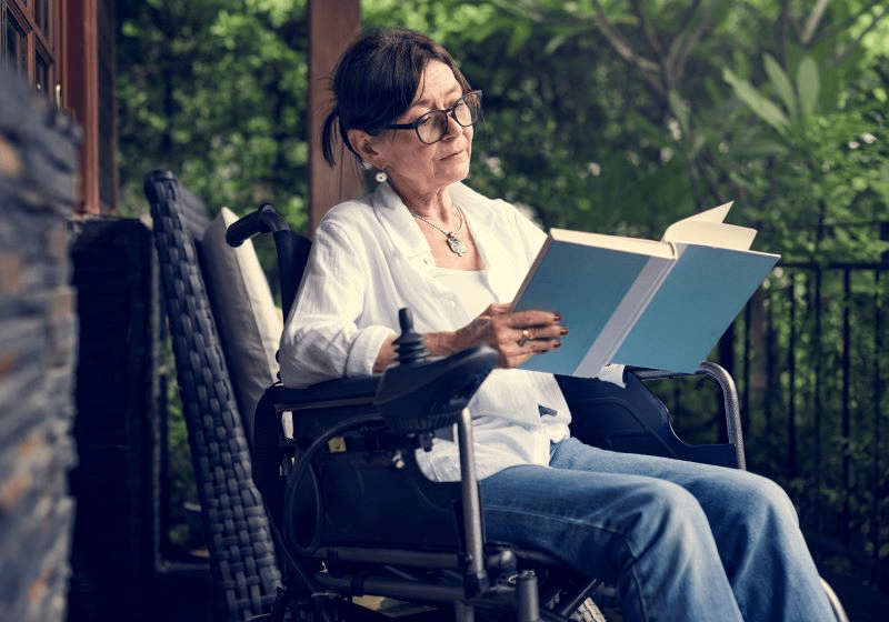 woman sitting a wheelchair reading a book