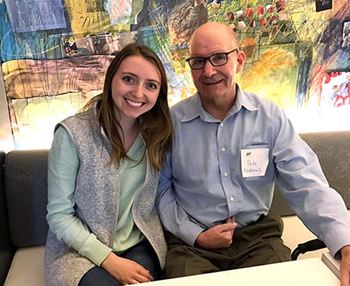 Justine Knight and Pete Andrews sitting at a table in a modern indoor setting smiling for the camera