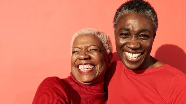 two people with big smiles on a coral background
