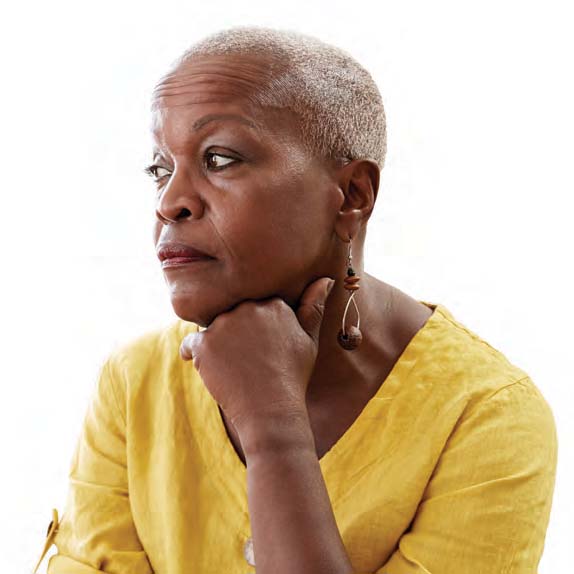 an older Black woman in a yellow top with a concerned expression on her face