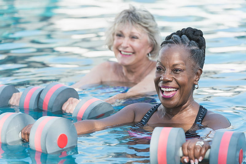a senior Black woman and friend doing water aerobics